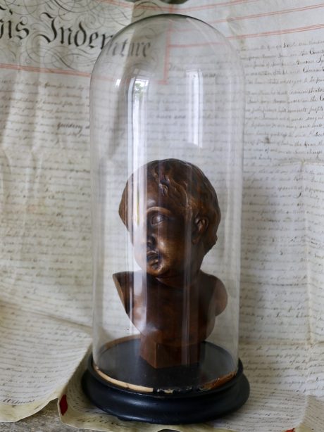 Hand carved bust of an infant in an antique dome