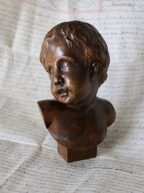 Hand carved bust of an infant in an antique dome
